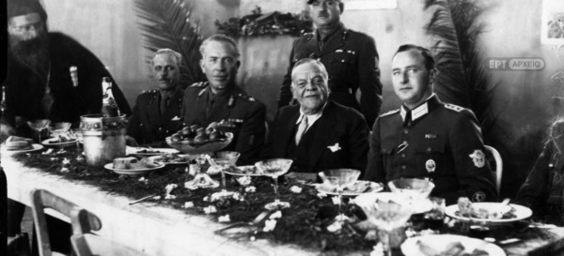 Ο διορισμένος από τις γερμανικές αρχές Κατοχής πρωθυπουργός Ιωάννης Ράλλης σε πασχαλινό γεύμα. Δεξιά του ο αντισυνταγματάρχης Βασίλειος Δερτιλής, διοικητής των Ταγμάτων Ασφαλείας και αριστερά του ο Γερμανός αξιωματικός Φίσερ, Αρχείο ΕΡΤ – Πέτρος Πουλίδης