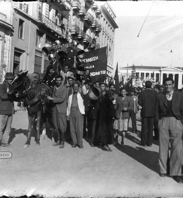 Εορτασμοί για την Απελευθέρωση. Μέλη του ΚΚΕ στη συμβολή των οδών Πανεπιστημίου και Κοραή. Κρατούν σημαίες και πανό και φωνάζουν συνθήματα χρησιμοποιώντας το χωνί, Αρχείο ΕΡΤ – Πέτρος Πουλίδης